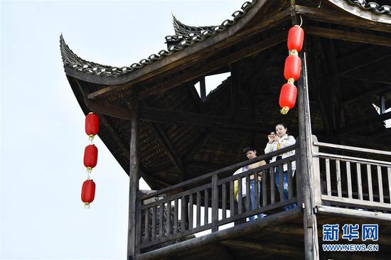  游客在重慶市武隆區(qū)黃鶯鄉(xiāng)復興村的觀景樓上欣賞田園景色（2019年3月28日攝）。 新華社記者 劉潺 攝